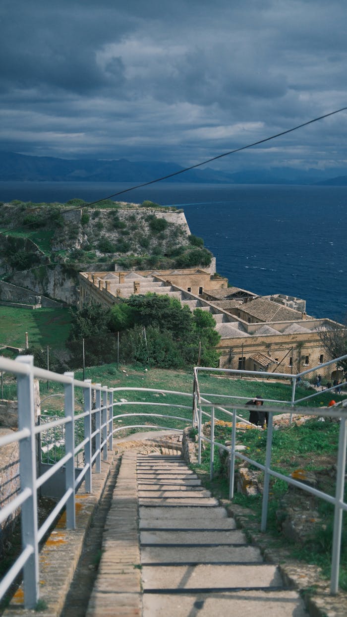 A scenic view of a historic coastal fortress overlooking the ocean under dramatic clouds.